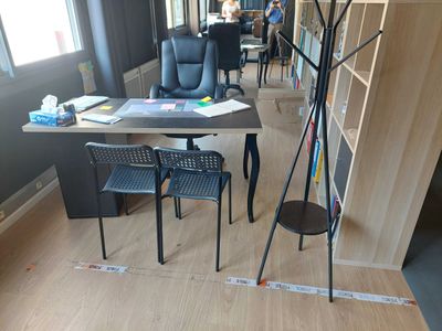 a room with a desk, chairs, and a lamp in it