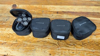trois étuis noirs posés sur une table en bois, à côté d'un casque audio