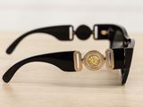black sunglasses with a gold medallion on the side of them