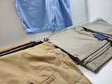 a pile of pants sitting on a bed next to a window