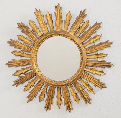 un motif doré en forme de rayons de soleil accroché au mur au-dessus d'un miroir