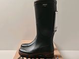 black rubber boots on top of a cardboard box on a white surface