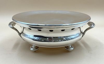 une assiette en argent posée sur un support, sur une table