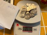 a pile of coins sitting on a scale next to a laptop