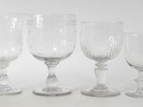 four wine glasses are lined up in a row on a white surface