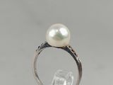 a close up of a ring with a pearl and diamonds on it