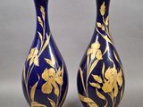 une paire de vases bleus et dorés ornés de fleurs sur fond gris
