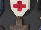 three medals and a cross are on a black surface