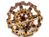 gold and garnett broochle with red stones on a white background