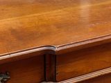 a close up of a wooden dresser with a metal handle