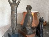 une statue représentant une femme et un chat assis sur une table