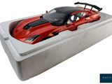 a red toy car in a white box on a white surface