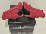 pair of red sued shoes sitting on top of a stack of books