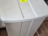 une poubelle blanche posée par terre à côté d'un radiateur