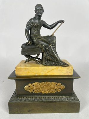 une statue antique en bronze représentant une femme assise sur une boîte