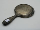 an old silver mirror with a monogram on it sitting on a table