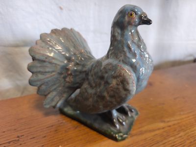 statue d'un oiseau posée sur une table en bois, avec un mur blanc en arrière-plan