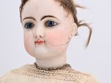 a small doll with blue eyes sitting on a white surface