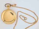 a gold pocket watch with a chain on a white surface