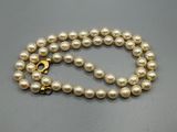 un collier de perles blanches avec un fermoir en or