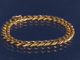 un gros plan d'un bracelet en or sur un fond bleu