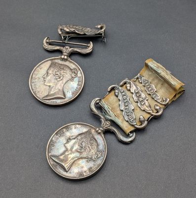 three silver medals and a clasp on a gray surface