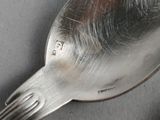 a silver spoon with a bird on it on a table