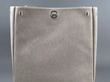 a beige canvas bag with a silver metal handle