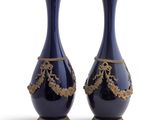pair of blue vases with gold decoration on stands against a white background