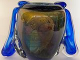 un vase en verre muni d'une anse bleue, posé sur une table