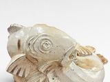 an image of a white sculpture of a fish on a wooden stand