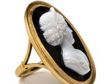 a close up of a gold ring with a black and white cameo of a woman