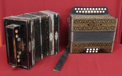two old accordions sitting on a red cloth with a red background