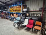 de nombreuses chaises et tables dans un entrepôt, avec une étagère remplie de chaises