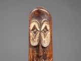 a carved wooden mask with two eyes and a nose