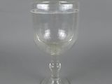 a clear glass goblet with a stem on a gray background