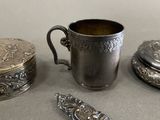 a silver cup sitting next to other silver objects on a table