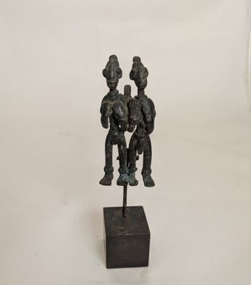 a bronze statue of three people sitting on a wooden base
