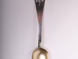 a silver spoon with a gold spoon handle hanging from the wall
