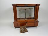 a small wooden clock with a pendulum on top of it