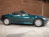 an image of a green convertible car parked in front of a brick wall