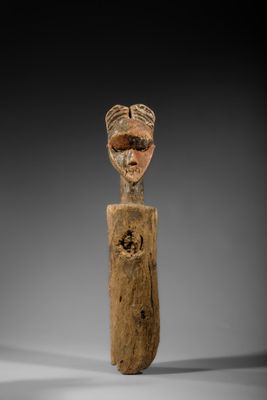 une vieille figurine en bois sur laquelle est représenté un visage