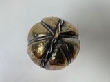 a gold and black bead on a white surface