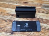 a nintendo switch next to a game controller on a wooden table