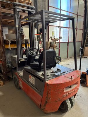 un chariot élévateur dans un entrepôt où il y a beaucoup de bois