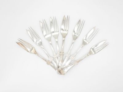 six fourchettes en argent disposées en cercle sur une surface blanche