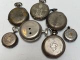 a lot of silver pocket watches sitting on a table