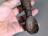 a person holding a wooden spoon with a pattern on it