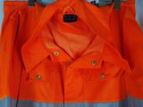 an orange work jacket hanging on a hanger on a wall