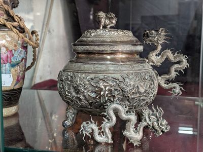 un vase en argent orné d'un dragon, exposé dans une vitrine